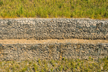 Stones in networks to protect against landslides of the soil
