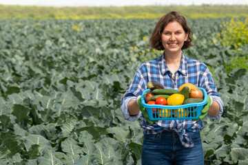 woman resting after work in the field and holds a basket with harvested vegetables. woman working on an agricultural field on a sunny day