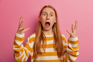 Emotional preteen girl goes crazy, screams outraged, keeps mouth widely opened, gestures with...