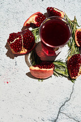 Pomegranate on a light background. Sliced ​​Pomegranate. Pomegranate juice on a light background. Juice in a glass.