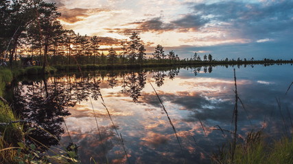 Fototapeta premium Beautiful summer sunset cloudy sky is reflecting in calm lake water. Picturesque landscape background as beauty of nature and environmental protection concept. Time lapse camera motion 4K UHD video.