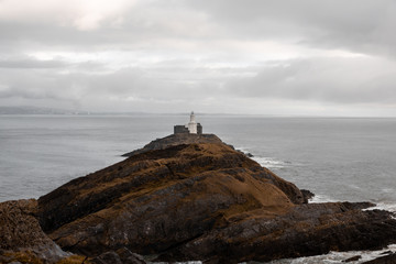 Isla con faro durante un día de tormenta en la costa de gales