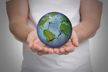 Man holding Earth with medical mask on light background, closeup. Concept of coronavirus outbreak
