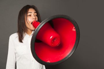 Young woman screaming with loudspeaker, cries expressing excitement, great emotion