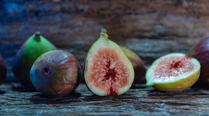 Fresh figs (Ficus carica) and halves on rustic wooden background...