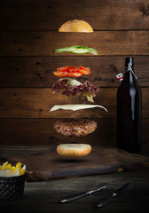 Burger mięsny z latającymi składnikami, na białym tle, z miejscem na tekst lub logo, czarne tło i jasne kolory - 333679699