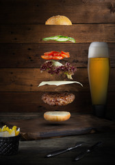 Burger mięsny z latającymi składnikami, na białym tle, z miejscem na tekst lub logo, czarne tło i jasne kolory - 333680492