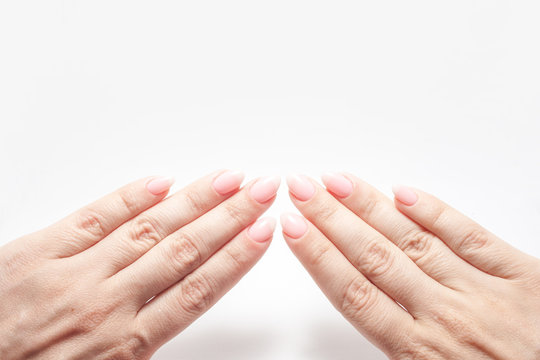 Women's hands with perfect Nude manicure. Nail Polish is a natural pale pink shade.