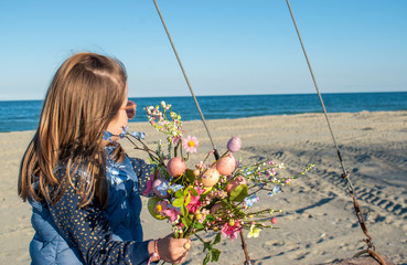 happy little girl with easter eggs flower bouquet by the sea. Happy Easter