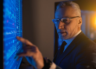 The old businessman working on the blue screen in the dark laboratory