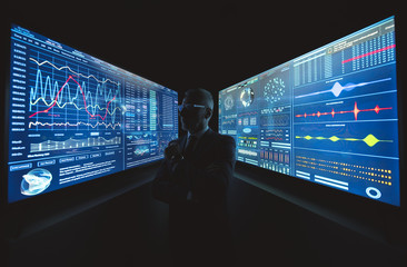 The old businessman standing near the big blue screen with graphics
