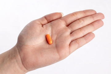 Orange pill in palm hand. medicines and vitamins