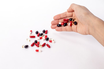 Colorfull medicine pills in left hand. red, white and black medicines and vitamins