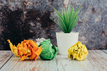 crumpled paper and green potted plant on wooden desk