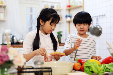 Asia two children are cooking food in the kitchen on a holiday in home.