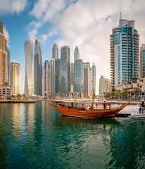 Panoramic view with modern skyscrapers and water pier of Dubai Marina at sunset, United Arab Emirates