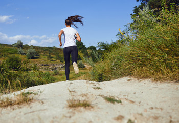 Obraz premium Girl runner runs along in nature in summer.