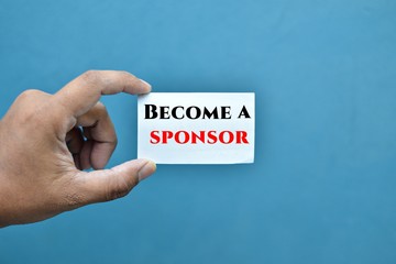 Hands holding business card written BECOME A SPONSOR.