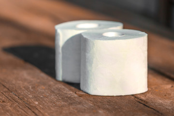 Two rolls of toilet paper lying on wooden boards