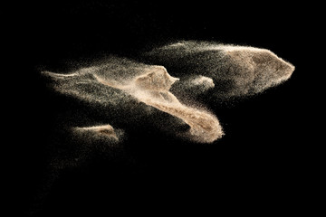 Brown colored sand splash.Dry river sand explosion isolated on black background. Abstract sand...