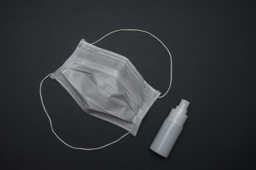 Hygienic face mask with white bottle hand sanitizer isolated on black background. Coronavirus prevention concept.