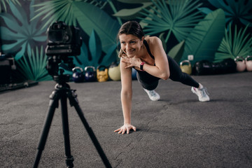 Young female fitness instructor making online training. Young fitness instructor shows how to exercise at home.