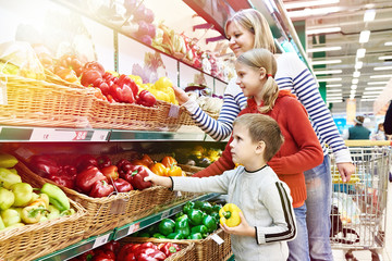 Mother and children with bell pepper in supermarket