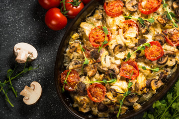 Baked meat with vegetables top view on black table.