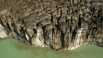 Aerial sideview on Black Glaciar covered with volcanic black ash. Black ice formation next to green lake waters. Cerro Tornador, Nahuel Huapi National Park Argentina, Patagonia