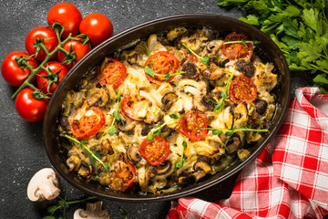Baked meat with vegetables top view on black table.