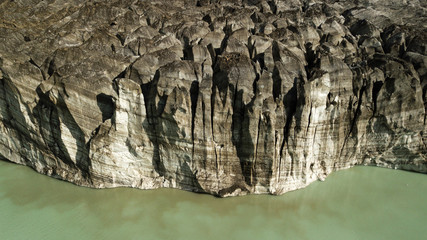 Aerial sideview on Black Glaciar covered with volcanic black ash. Black ice formation next to green lake waters. Cerro Tornador, Nahuel Huapi National Park Argentina, Patagonia