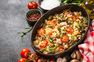 Baked meat with vegetables on black table.