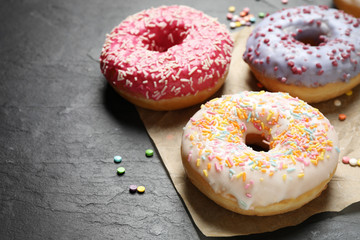 Yummy donuts with sprinkles on dark background, closeup