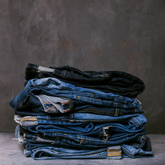 Stack of jeans on a concrete background. Selvedge jeans. Copy space.