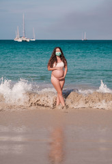  pregnant woman on beach, wearing protective mask from virus