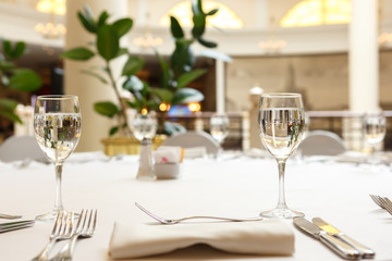 Empty glasses and white napkins are installed in the restaurant on the table.