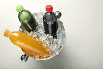 Different soda drinks in metal bucket with ice on light grey table, top view © New Africa
