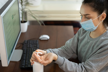 Coronavirus. Business woman working from home wearing protective mask. Business woman in quarantine for coronavirus wearing protective mask. Working from home. Cleaning her hands with sanitizer gel.