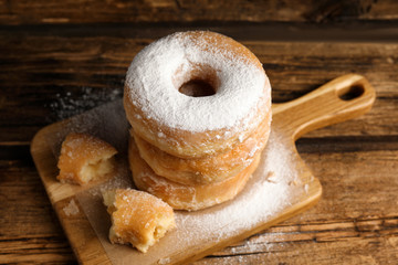 Delicious donuts with powdered sugar on wooden table