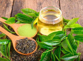 dried green tea leaf and powder on wooden background