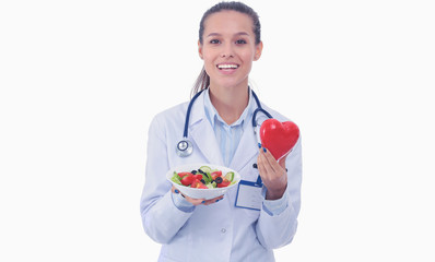 Portrait of a beautiful woman doctor holding a plate with fresh vegetables and red heart. Woman doctors.