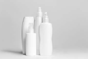Set of cosmetic products in white and grey containers on light background.