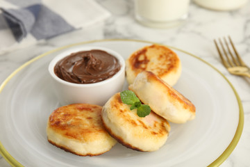 Delicious cottage cheese pancakes with chocolate paste on plate, closeup