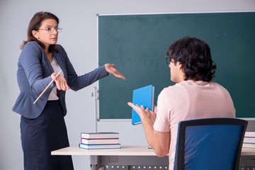 Old female teacher and male student in the classroom
