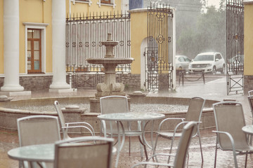 empty table and chairs in a cafe in the rain