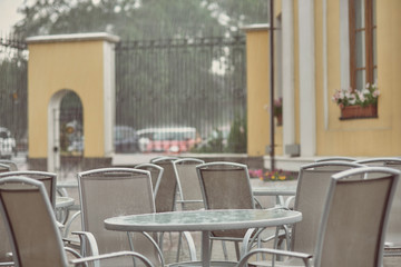 empty table and chairs in a cafe in the rain
