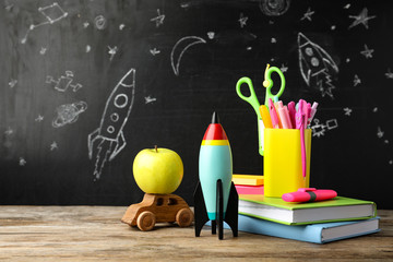 Bright toy rocket, car and school supplies on wooden table