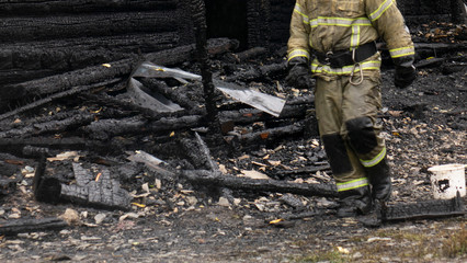 A fireman in a burned-out wooden house .