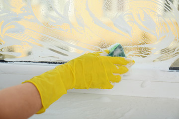 Woman cleaning window with sponge, closeup view