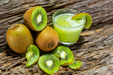 Fruits and Kiwi juice fresh and in halves on a woody background